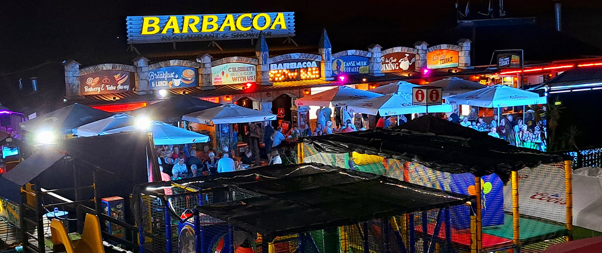 Barbacoa Restaurant & Showbar iluminado por la noche en El Puerto de Santa María, Cádiz, con terraza animada y zona infantil